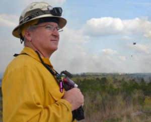 Paul Catlett provides oversight as Florida National Guard helicopters perform water-bucket operations for controlled burns used for training at Camp Blanding, April 2014.